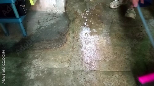 Person using pink squeegee to sweep water on concrete floor