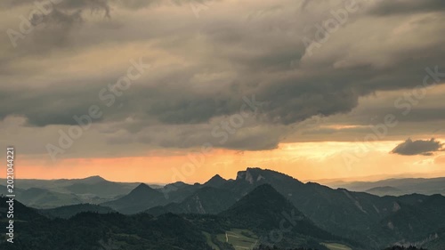 Cinematic timelapse of sunset in Pieniny National Park, Poland. View of Three Crowns peaks with dramatic storm clouds and sun rays hitting the valley.