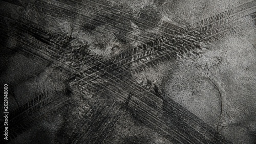 Tire marks on weathered cement floor create an abstract industrial pattern featuring dark rubber skid marks across a gritty vintage concrete texture