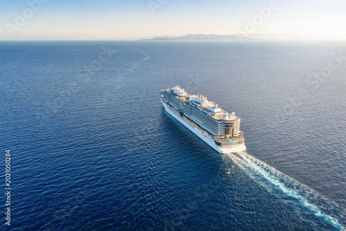 Fotografie High aerial view of a cruise ship sailing over blue ocean into the sunset with c