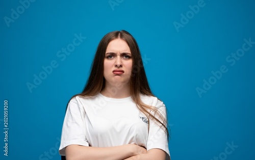 Фотография Young woman reacting with disgust or displeasure, frowning with arms crossed aga