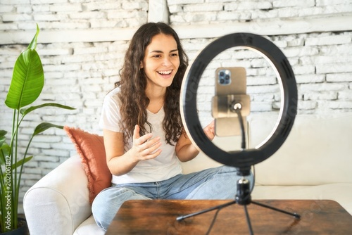 Enthusiastic young woman recording a video for social media with a smartphone and ring light