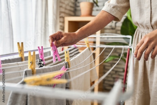 Person's hand hanging clothes with a clothespin on an indoor drying rack