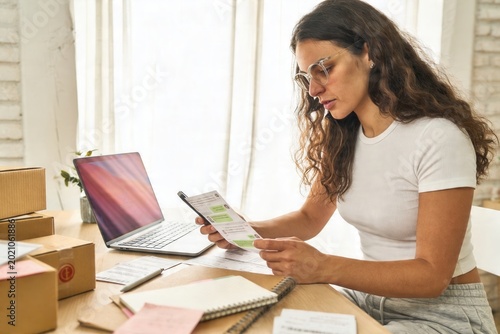 Woman managing online sales, packaging orders and shipping products