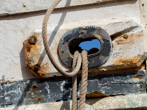 Old maritime rope and rusted metal fitting on weathered wooden fishing boat detail