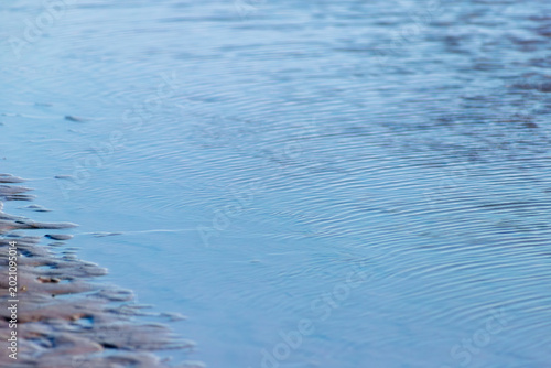 Φωτογραφία A horizontal close-up of blue water ripples on a shallow surface, likely a tidal pool or the edge of the sea