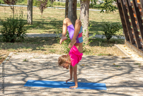 Schilderij op canvas Child performing a handstand with bent legs outdoors