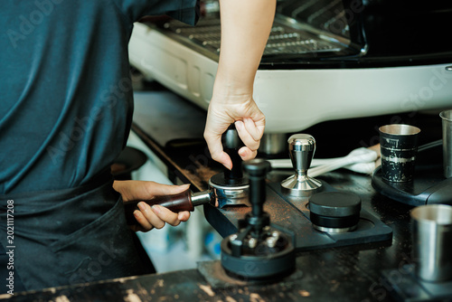 Tableau sur toile Close-up of a professional barista's hand using a metal tamper to press ground coffee in a portafilter