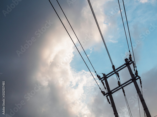 青空と雲に伸びる電線と電柱　日常を支える社会インフラのイメージ
