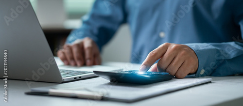 Photos The concept of tax planning and tax calculation involves business people using laptops and calculators to fill out online income tax forms and make payments