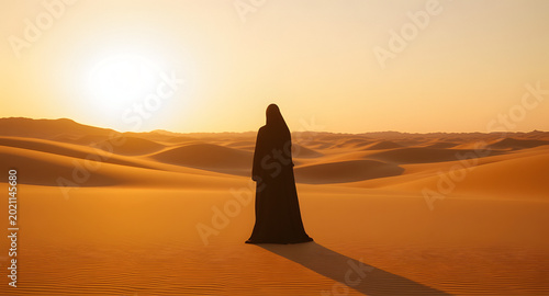 Person in flowing robe faces vast sand dunes during warm evening light. Horizon glows with soft orange hues.