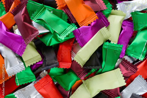 Full frame background of wrapped sweet treats in blank multicolored packaging. Ideal for festive holiday designs, marketing mockups, and vibrant dessert advertising. Photo