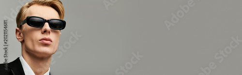 Fotografija Stylish young man in black suit and sunglasses exuding confidence and charm