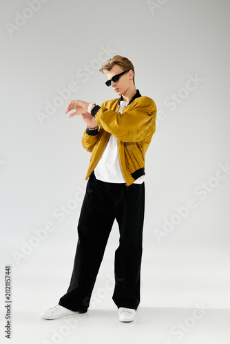 Fashion forward young man showcases style in a striking outfit against a simple backdrop