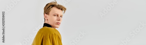 Obraz na płótnie Stylish young man in a golden jacket exudes confidence with a modern flair