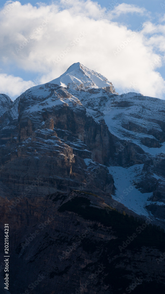 Fototapeta premium Snow capped mountain peak with clouds in blue sky