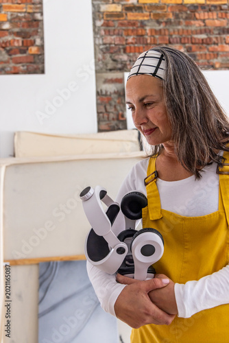 Artist in yellow grabbing headphones near canvases preparing recording while waveform animating