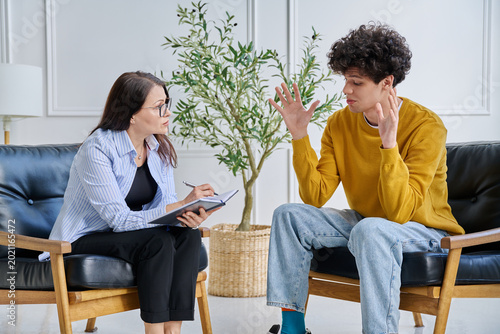 Bild auf Leinwand Young male patient in therapy session talking with female psychotherapist