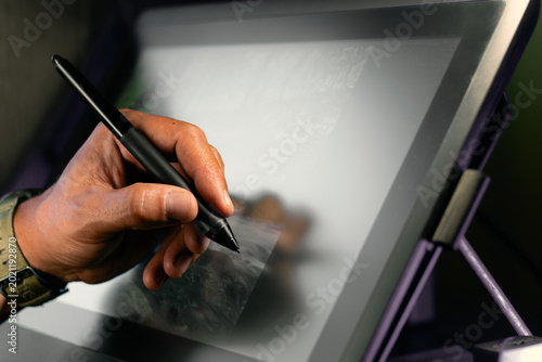 фотографія Close-up of left-handed digital artist drawing on graphic tablet with stylus pen