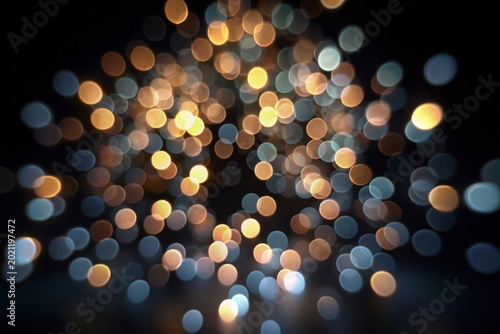 Shimmering Night Lights. Dense cluster of soft, circular bokeh lights in warm gold and cool blue tones, creating magical and festive atmosphere against dark background