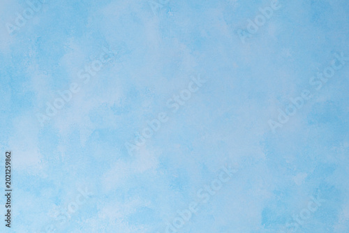Sky blue textured background with soft white cloud-like strokes.