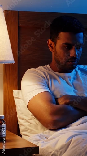 Man with insomnia lies awake in bed at night unable to sleep. Male experiences sleep disorder in bedroom. Man suffering insomnia thinks in bed. Sleep problems keep man awake during night rest.