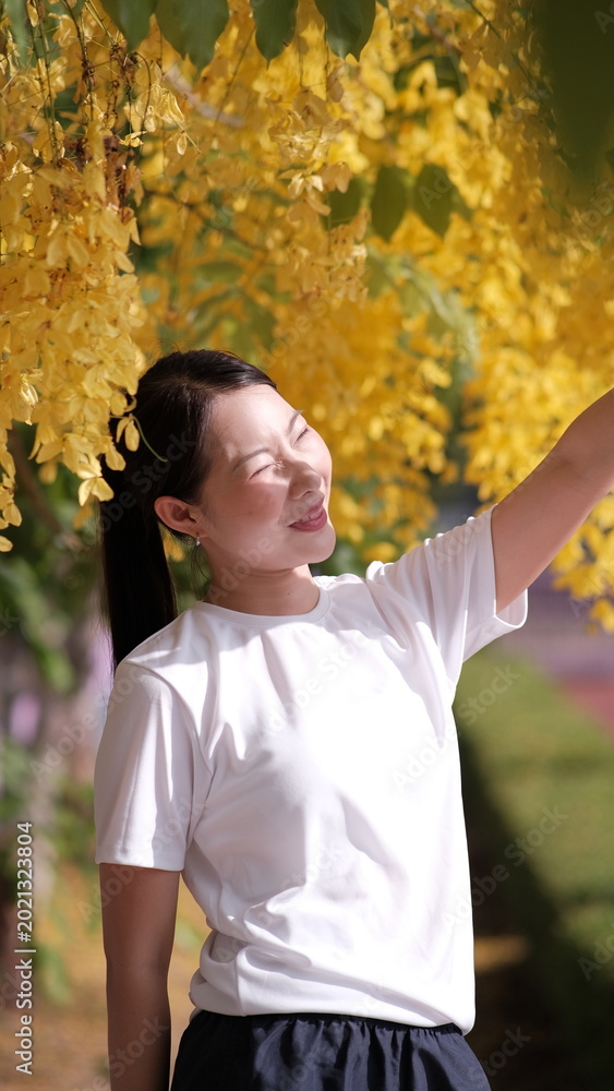 Fototapeta premium Young girl under yellow flower, Person standing under blooming yellow flower tree outdoors in spring