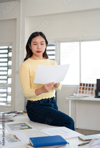 Architectural woman working on blueprint in office.Business of Real estate, home decoration and renovation concept. Interior designer in office working on a project.