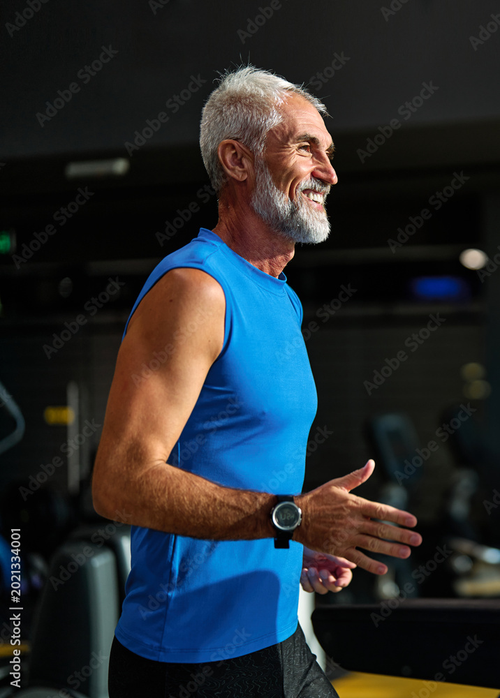 Fototapeta premium Portrait of a senior man exercising in a gym, mature couple running using threadmill machine equipment, healthy lifestyle and cardio exercise at fitness club concepts, vitality and active senior, coac