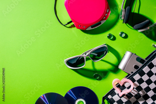 Silver sunglasses and pink CD player on vibrant green retro background