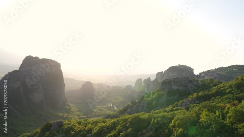 Tourists Watch Sunset at Holy Monastery of Rousanou Meteora Greece. Pan from People to Epic View Above Rocks Mountains to Famous Church Unesco