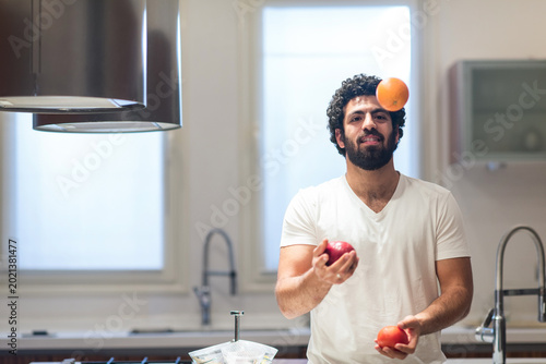 Tablou pe pânză Middle Eastern man preparing iftar in a modern home kitchen while juggling fruit
