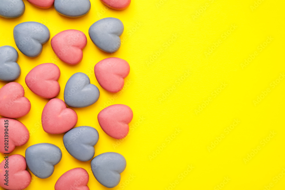 Obraz premium Yummy heart shaped candies on yellow background, flat lay. Space for text