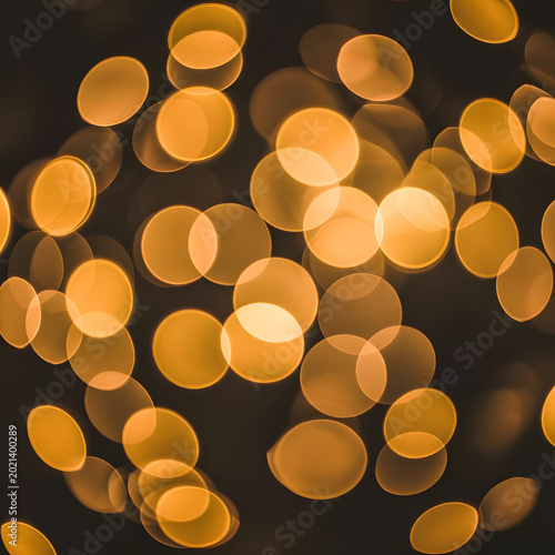 golden bokeh light circles glowing softly in dark background with warm abstract pattern
