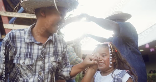 A group of happy Brazilian children wearing traditional straw hats and plaid shirts dance the quadrilha during a vibrant Festa Junina celebration, showcasing cultural heritage and joyful spirit