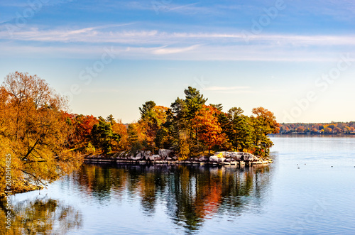 Rocky shored island on a river with bright autumn colored trees.