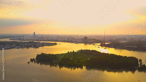 Photography AERIAL: Flying over the river and towards Vietnamese city at golden sunrise