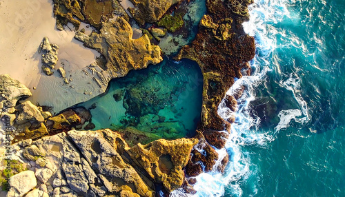 Aerial View of a Natural Heart Shaped Ocean Pool Surrounded by Rocky Coastline and Turquoise Water