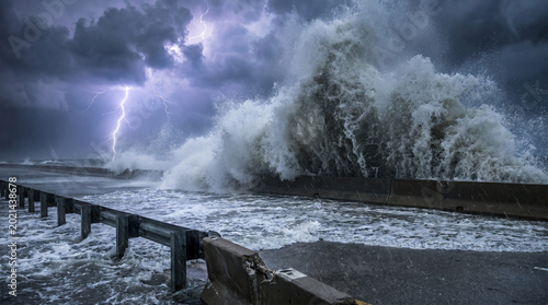 Powerful waves crashing on coastal road during storm and lightning  