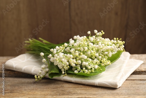 Beautiful lily-of-the-valley flowers on wooden table, closeup