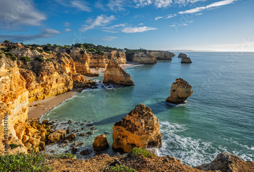 View of Praia da Marinha beach in Algarve, Portugal, with ocean cliffs, sea stacks and clear blue water.