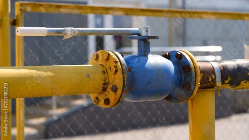 Konstfotografi A blue industrial ball valve connected to a metal pipeline with rusty bolted fla