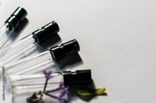 Foto Small glass perfume sample vials with black spray heads on a white background