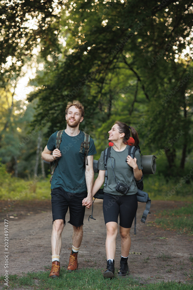 Fototapeta premium Photo of couple standing in forest at summer with a backpack
