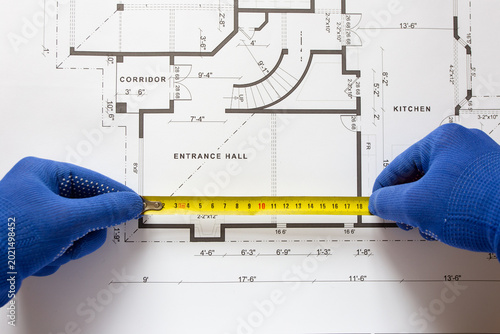 Fotografía A construction engineer makes surveys on a paper drawing of a house using a measuring tape, close-up of the builder's hand and tape measure