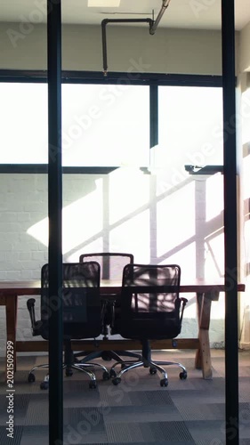 Vertical video: Sliding camera centering trestle table and two chairs in office showing shadows