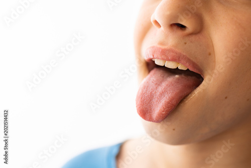 Child sticking out tongue. Close up view of mouth showing tongue and teeth. Expression of playfulness, silliness or medical examination of health. Dental care or body part concept.