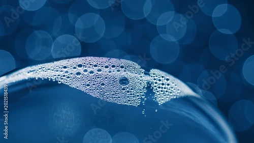 A macro shot of a vibrant blue fish swimming underwater in a clean aquarium, surrounded by glowing bubbles and light patterns reflecting through the liquid ocean background