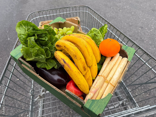 Fresh grocery cart with bananas, lettuce, and assorted produce in cardboard box
