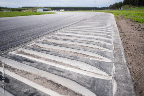Fotografie Perspective view of a concrete rumble strip on a professional race track curve,